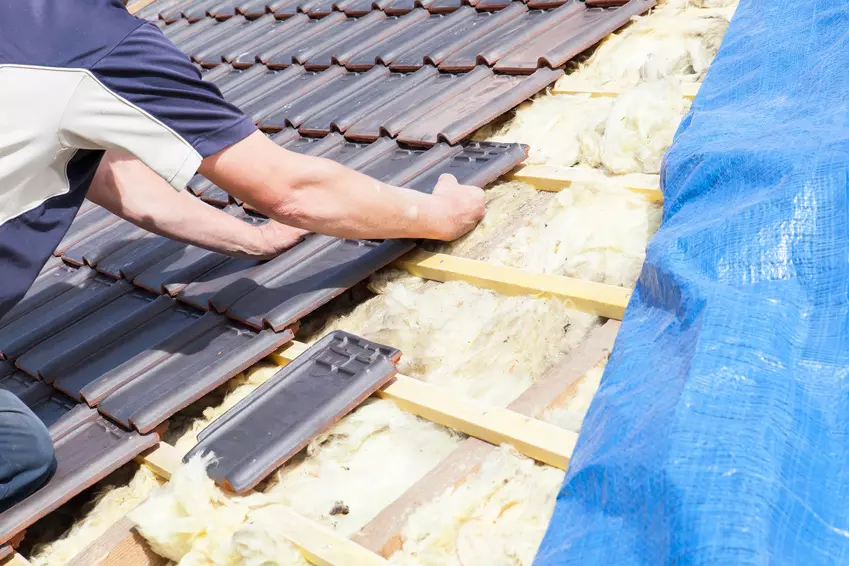 Mężczyzna układa dachówki na dachu